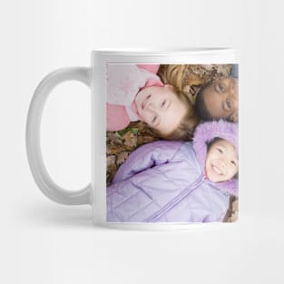 Smiling children lying on autumn leaves (F001/1826) Mug